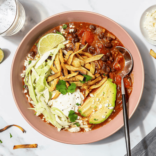 A bowl of fresh and appetizing vegan chili topped with avocado, lime, and a dollop of sour cream, exemplifying Fresh Prep’s commitment to delivering healthy and flavourful meals in Vancouver.