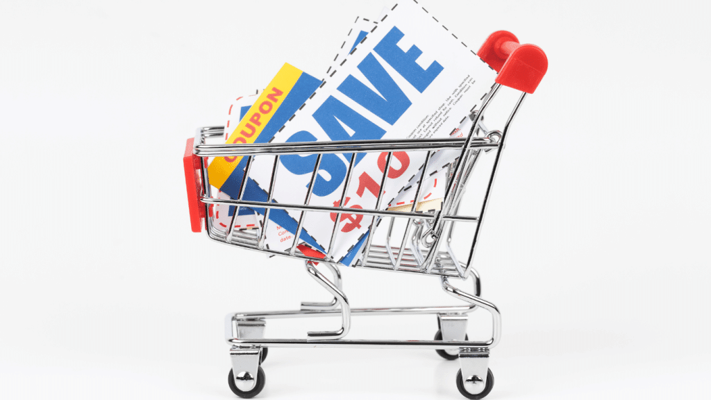 The image shows a miniature shopping cart against a white background, filled with colorful coupon flyers that prominently display the word "SAVE" and various discount percentages, symbolizing savings on purchases. The coupons in the cart represent a range of deals and discounts, with the bold lettering catching the viewer's eye and emphasizing the potential for cost reduction. This visual metaphor illustrates the concept of couponing and deal-hunting as an effective strategy for reducing grocery bills in 2024, suitable for a section titled "Couponing and Deal Hunting in 2024: How to Save Money on Groceries". The focus on coupons highlights the importance of seeking out discounts to manage and minimize grocery expenses.